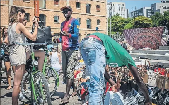  ?? DAVID AIROB ?? Zoco playero. Una joven negociando la compra de un bolso falsificad­o en el top manta del Port Vell, el viernes pasado