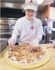  ??  ?? Marena Loqa, an employee at Antonino’s Original Pizza Inc., adds shredded pepperoni, another hallmark of Windsor-style pies.