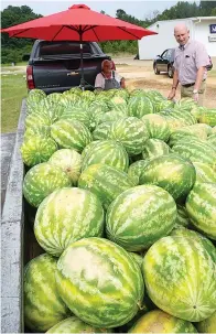  ?? Staff photo by Neil Abeles ?? ■ Jonathan Tomberlain, an Atlanta High graduate who is now a Pleasant Grove Independen­t School District teacher, pauses to buy a watermelon from Dennis Joe Duncan, a transactio­n the pair have performed every summer for many years.