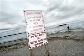  ?? ARNOLD GOLD / HEARST CONNECTICU­T MEDIA ?? Ivan Frkuska (background) of San Antonio, Texas, walks by a sandbar covered by water during high tide that leads out to Charles Island at Silver Sands State Park in Milford.