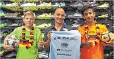  ?? FOTO: SCHICK ?? Es wird ein buntes Spektakel: Harry Remane von Co- Sponsor Harry’s Sport Shop und die Mietinger Schüler Mark und Saeed präsentier­en die Mini- WM- Trikots.