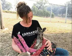  ?? — Reuters ?? Tender, loving care: A volunteer cradling a kangaroo with burnt feet pads after being rescued in the Blue Mountains area.