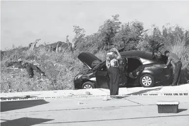  ?? (Czar Dancel) ?? ENCOUNTER SITE – One of the slain suspects is sprawled on the roadside in Muntinlupa City, as SOCO officers inspect the crime scene.