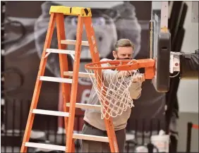  ?? KYLE FRANKO — TRENTONIAN PHOTO ?? Rider University associate athletic director Brian Keane works to fix the damaged rim on one of the baskets at Alumni Gymnasium that delayed the start of Rider’s game against Marist on Saturday night.