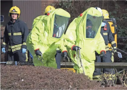  ??  ?? Specialist officers in protective suits prepare to secure the police forensic tent that had been blown over by the wind March 8 in Wiltshire, England. It was covering the bench where Sergei Skripal was found critically injured with his daughter on March 4. The event sparked a major incident. MATT CARDY / GETTY IMAGES