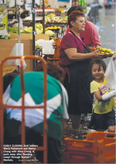  ?? Picture: STEWART McLEAN ?? EARLY CLOSING: Stall holders Maria Pulverenti and Nancy Chang with Alina Chang, 6, pack away after flooding swept through Rusty’s Markets.