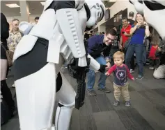  ??  ?? Andrew Bowen, 1½, fist-bumps with Storm Troopers as parents James and Martha photograph the close encounter Saturday at Silicon Valley Comic Con.