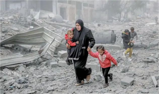  ?? Agence France-presse ?? ↑
A Palestinia­n woman and her children flee an area after an Israeli bombardmen­t in central Gaza City on Monday.