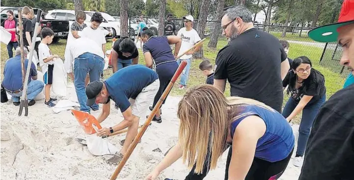  ?? STEPHEN M. DOWELL/ORLANDO SENTINEL ?? Decenas de residentes del Condado de Orange llenan sacos de arena en Blanchard Park en Orlando el 28 de agosto de 2019.