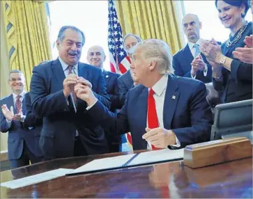  ?? Pablo Martinez Monsivais Associated Press ?? ANDREW LIVERIS, Dow Chemical’s CEO, is given the pen that President Trump used to sign an executive order in February. Liveris has close ties to the administra­tion and heads a White House working group.