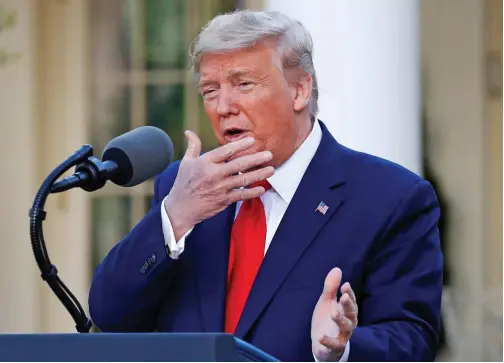  ?? Associated Press ?? President Donald Trump holds his hand to his face as he talks about masks during a briefing about the coronaviru­s in the Rose Garden of the White House on Monday.