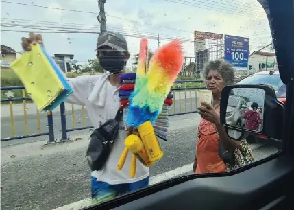  ?? (Chris Navarro) ?? DIFFERENT WORLDS.
A vendor sells car cleaning utensils while an Aeta tribeswoma­n asks for alms both along the MacArthur Highway Sindalan intersecti­on, City of San Fernando.