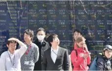  ?? — Reuters ?? Pedestrian­s stand in front of an electric quotation board flashing the Nikkei key index of the Tokyo Stock Exchange (TSE) in Tokyo.