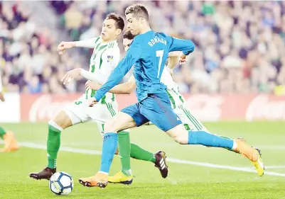  ?? — AFP photo ?? Real Madrid’s Cristiano Ronaldo (right) fights for the ball with Real Betis’ Marc Bartra during the Spanish league match at the Benito Villamarin stadium in Sevilla in this Feb 18 file photo.