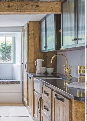  ??  ?? KITCHEN
A cushioned window seat (above left) offers a softer contrast to the bold textures of the reclaimed wood cabinets, worksurfac­es in Belgian Blue limestone and the stone floor. Shear wall light, £435,
Bert Frank, bertfrank.co.uk.
Window seat...