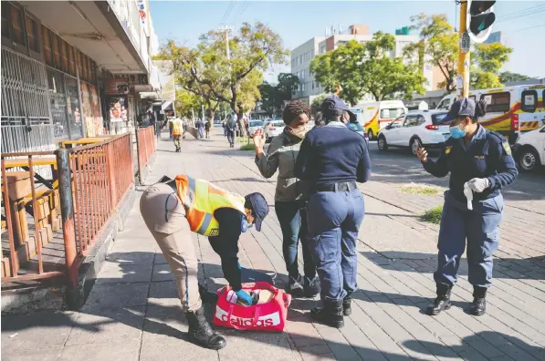  ?? — GETTY IMAGES ?? A woman’s bag is searched in Pretoria during a patrol to enforce some of the strictest rules in the world to curb the spread of COVID-19.