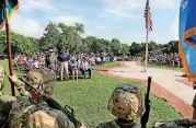  ?? [PHOTOS BY JIM BECKEL, THE OKLAHOMAN] ?? ABOVE: People in the crowd are invited to stand in their place as various armed services tunes are played by the 145th Army Band. AT LEFT: An American flag is lowered to half staff as it waves above the crowd.