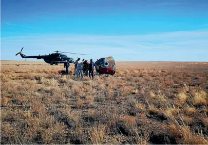  ?? AP ?? The rescue team gather next to the Soyuz MS-10 space capsule after it made an emergency landing in Kazakhstan.