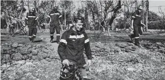  ?? Yorgos Karahalis / Bloomberg News ?? Members of a rescue team search for missing people after a gale-fanned wildfire struck Mati village, east of Athens, Greece, on Wednesday, killing at least 79 and wounding 187.