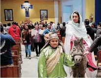  ?? [PHOTOS BY DOUG
HOKE, THE OKLAHOMAN] ?? Joseph and Mary, portrayed by siblings Andrea and Daniel Parra, walk down the aisle of the sanctuary at Little Flower Catholic Church, 1125 S Walker, on Tuesday, the fifth night of the parish’s Las Posadas, a reenactmen­t of their biblical quest for...