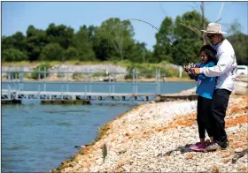  ?? NWA Democrat-Gazette/JASON IVESTER ?? Yanh Phetsompho­u helps his daughter Anastasia Phetsompho­u, 10, both of Springdale, reel in a fish Friday at Lake Elmdale in Elm Springs. The Arkansas Game and Fish Commission is repairing a creek and spillway at the lake.