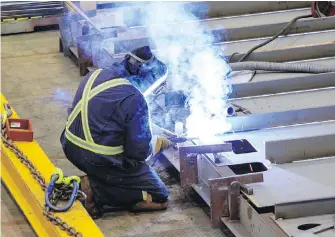  ??  ?? A Seaspan welder builds a ship section at the company’s Vancouver yard.