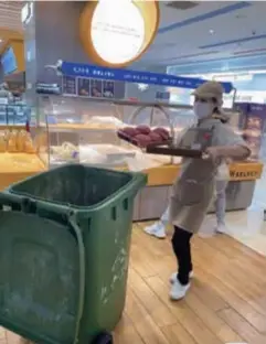  ?? ?? An employee discards unsold bread at a bakery in Chengdu, Sichuan Province.