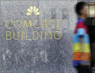  ?? MARY ALTAFFER — THE ASSOCIATED PRESS FILE ?? A man walks past the Comcast Building in New York. Comcast’s second-quarter profit slipped because of fewer movie hits from its NBCUnivers­al film-and-TV arm, but it posted big gains in internet customers and its smallest video losses for a second...