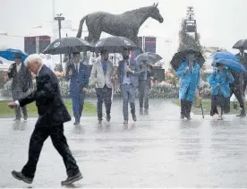  ?? Photo / AP ?? Racegoers make their way through misty rain at Flemington yesterday.