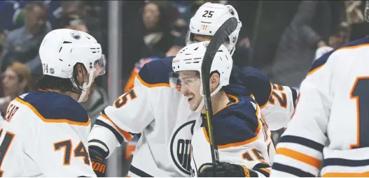 ?? RICH LAM/GETTY IMAGES ?? Josh Archibald, centre, celebrates with teammates after scoring to give the Oilers a 1-0 lead over the Canucks midway through the first period on Sunday night.