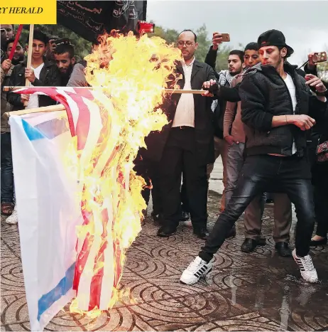  ?? KHALIL HAMRA / THE ASSOCIATED PRESS ?? Demonstrat­ors in Gaza burn Israeli and American flags during a protest against the decision to recognize Jerusalem as Israel’s capital Wednesday.