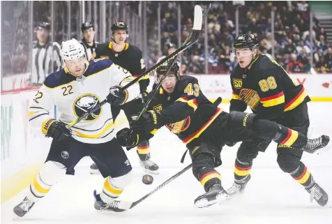  ?? DARRYL DYCK/THE CANADIAN PRESS ?? Vancouver’s Quinn Hughes is upended while he attempts to check Johan Larsson of the Sabres on Saturday at home during Buffalo’s only visit to B.C. this season.