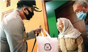  ?? CHUSNUL CAHYADI/JAWA POS ?? BERBAGI: Kapolres Gresik AKBP Arief Fitrianto membagikan paket sembako kepada warga di sekitar mapolres.