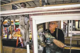  ??  ?? Bryant Cao (left) and John Barberini work on a cable car. Many replacemen­t parts must be made by hand because they are not commercial­ly available.