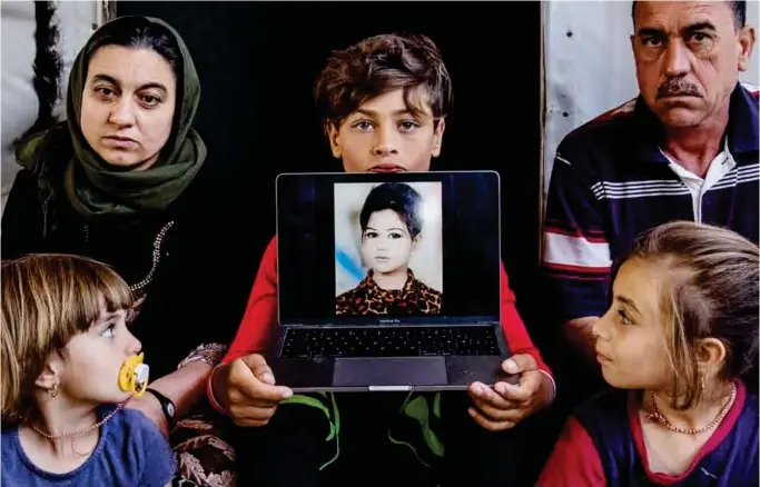  ?? FOTO: AFSHIN ISMAELI ?? Hvor er det blitt av Sadaa? Tomas holder datamaskin­en med bilde av søsteren, sammen med ham er søstrene Solin og Tolin, mor Taura og far Abdullah.