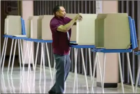  ?? (AP/Milwaukee Journal-Sentinel/Mike De Sisti) ?? Steven Rogers sets up voting booths Monday at South Division High School in Milwaukee.