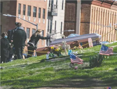  ?? JEENAH MOON / REUTERS FILES ?? With two coffins on the ground, masked mourners observing physical distancing attend a funeral at The Green-Wood
Cemetery during the outbreak of the cor onavirus disease (COVID-19) in the Brooklyn borough of New York City.