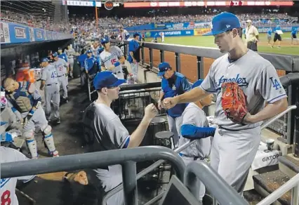  ?? Photograph­s by Julie Jacobson Associated Press ?? YU DARVISH IS GREETED in the dugout by fellow Dodgers starter Alex Wood after the sixth inning. Darvish made a great first impression with his new team with 10 strikeouts in seven innings, giving up three hits and walking only one against the Mets.