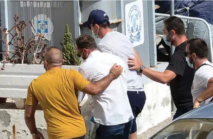  ??  ?? Manchester United captain Harry Maguire, with the blue cap, center, escorted by plain clothed police officers at the police station on the Aegean island of Syros, Greece