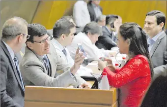  ??  ?? El diputado Walter Harms (ANR, cartista) muestra su teléfono celular a la líder de la bancada abdista, Jazmín Narváez (ANR, Añetete) durante la sesión en Diputados.