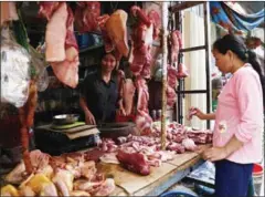  ?? HENG CHIVOAN ?? A woman purchases pork from a meat vendor yesterday in Phnom Penh.