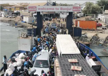  ?? JON GAMBRELL/THE ASSOCIATED PRESS ?? Passengers board a ferry in the bustling harbour in Banjul, Gambia, one of Africa’s poorest countries, where cultural rewards await intrepid travellers.