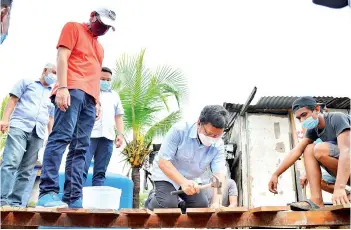  ??  ?? Azis watches Shafie giving villagers a helping hand in repairing a bridge in the village.