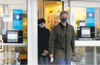  ?? NAM Y. HUH AP ?? Shoppers wear masks as they leave a retail store in Downers Grove, Ill., Friday. Across the U.S. contact tracers are reporting diagnosed individual­s say they gathered with people from outside their home for Thanksgivi­ng.