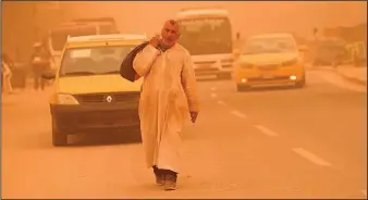  ?? ?? A man walks on a street during a sandstorm.
