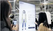  ?? Photo / Bloomberg ?? Using a touch screen to ‘try on’ clothes at a preview of GU’s new outlet.
