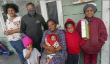  ?? Steve Mellon/Post-Gazette ?? Michael Martin of Three Rivers Youth gathers with Kayla Roberson and her family on her porch in Allentown on Nov. 27. From left are daughters Hannah, 14, and Heaven, 3; Mr. Martin; Ms. Roberson with son Jeremy, 3 months; and sons Darnell, 8, and Jeremiah, 10.