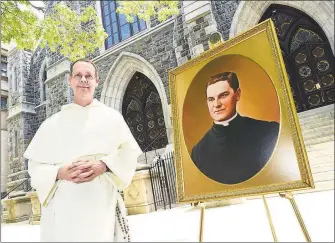  ?? Arnold Gold / Hearst Connecticu­t Media ?? The Rev. John Paul Walker stands in front of St. Mary’s Church in New Haven on Wednesday with a portrait of the Rev. Michael McGivney, who founded the Knights of Columbus.