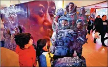  ?? ZHU XINGXIN / CHINA DAILY ?? Moviegoers check out a poster promoting the Chinese sci-fi blockbuste­r The Wandering Earth on Sunday in Beijing.