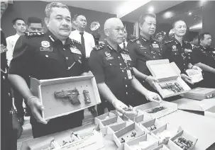  ?? — Gambar Bernama ?? HASIL RAMPASAN: Mohmad Salleh (dua kiri) bersama Chuah Ghee Lye (tiga kiri) dan pegawainya menunjukka­n empat pucuk pistol bersama 151 butir peluru hidup, tiga pasang gari serta dua bungkusan dadah jenis heroin dan ketamin kepada pihak media ketika...